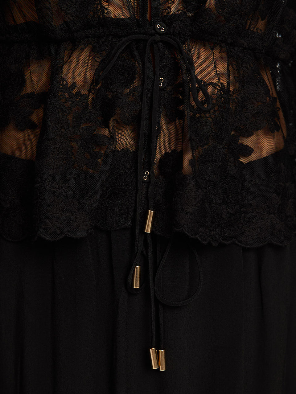 Close up image of lace top and black skirt  with tie up details