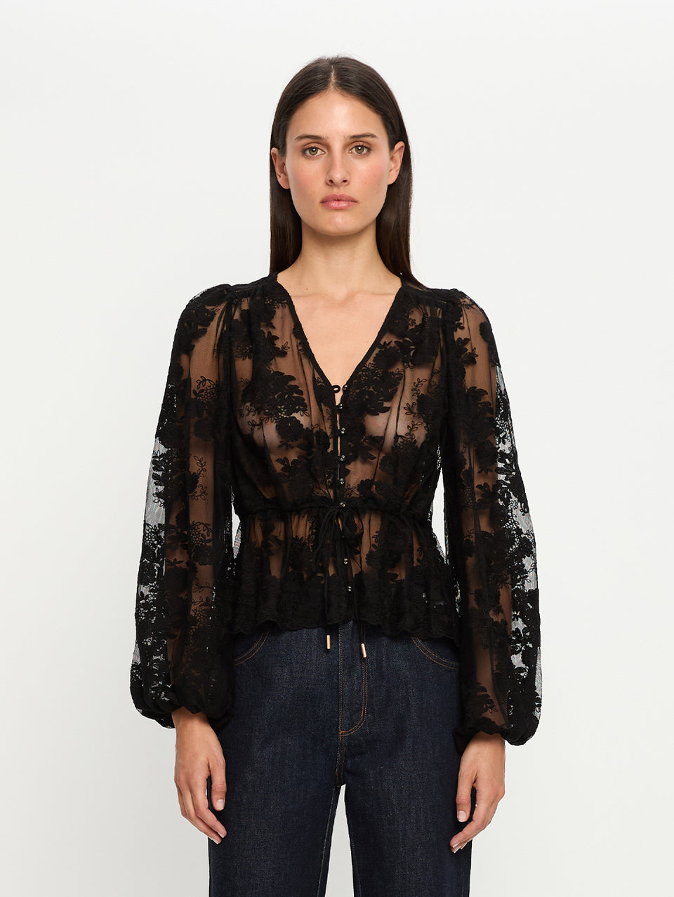 Woman wearing a black sheer blouse with long sleeves on a white background
