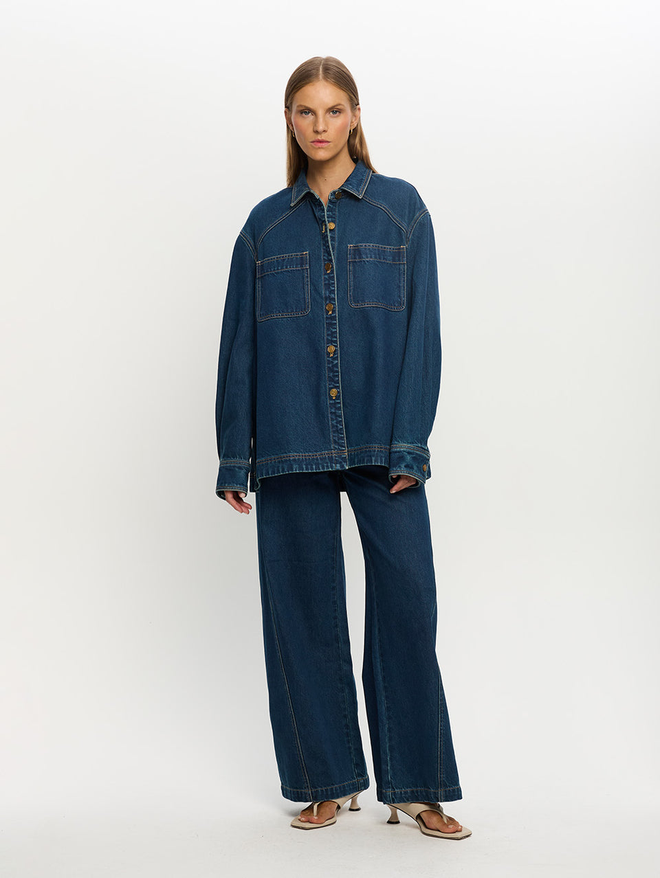 Woman wearing a blue denim jacket and pants on a white background