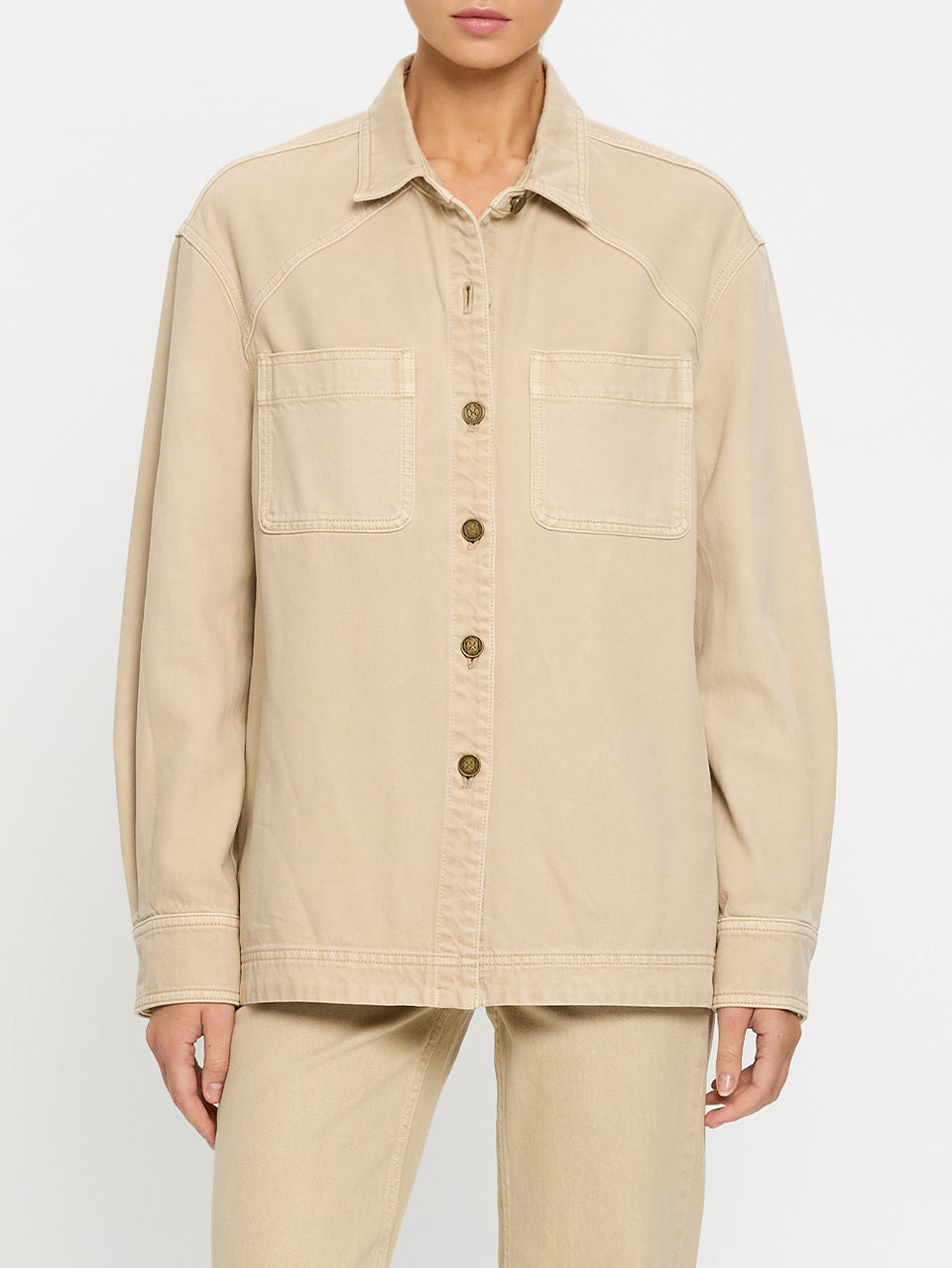 Woman wearing a beige denim shirt and jeans on a white background