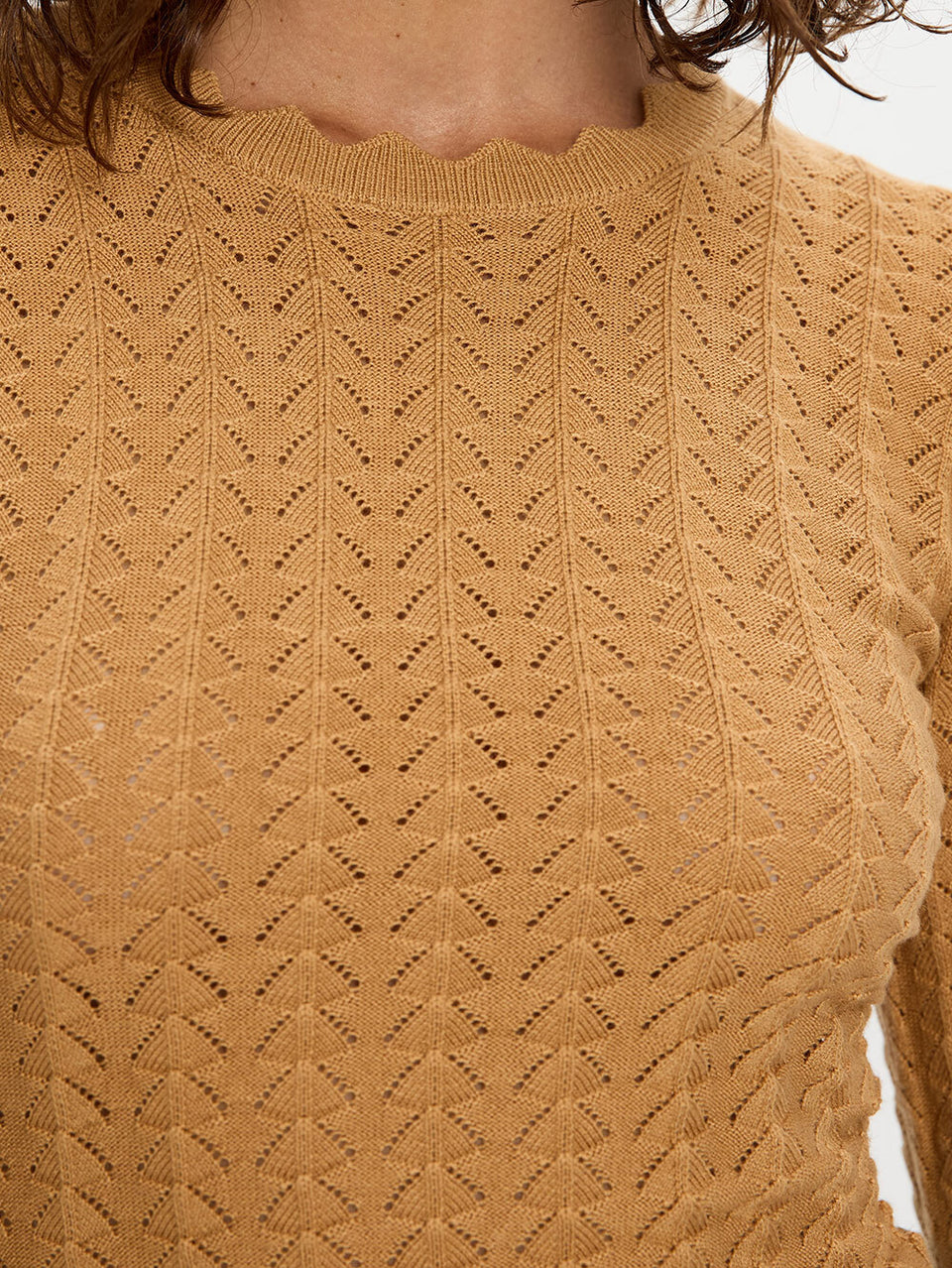 Close-up of a mustard yellow sweater with a textured pattern.