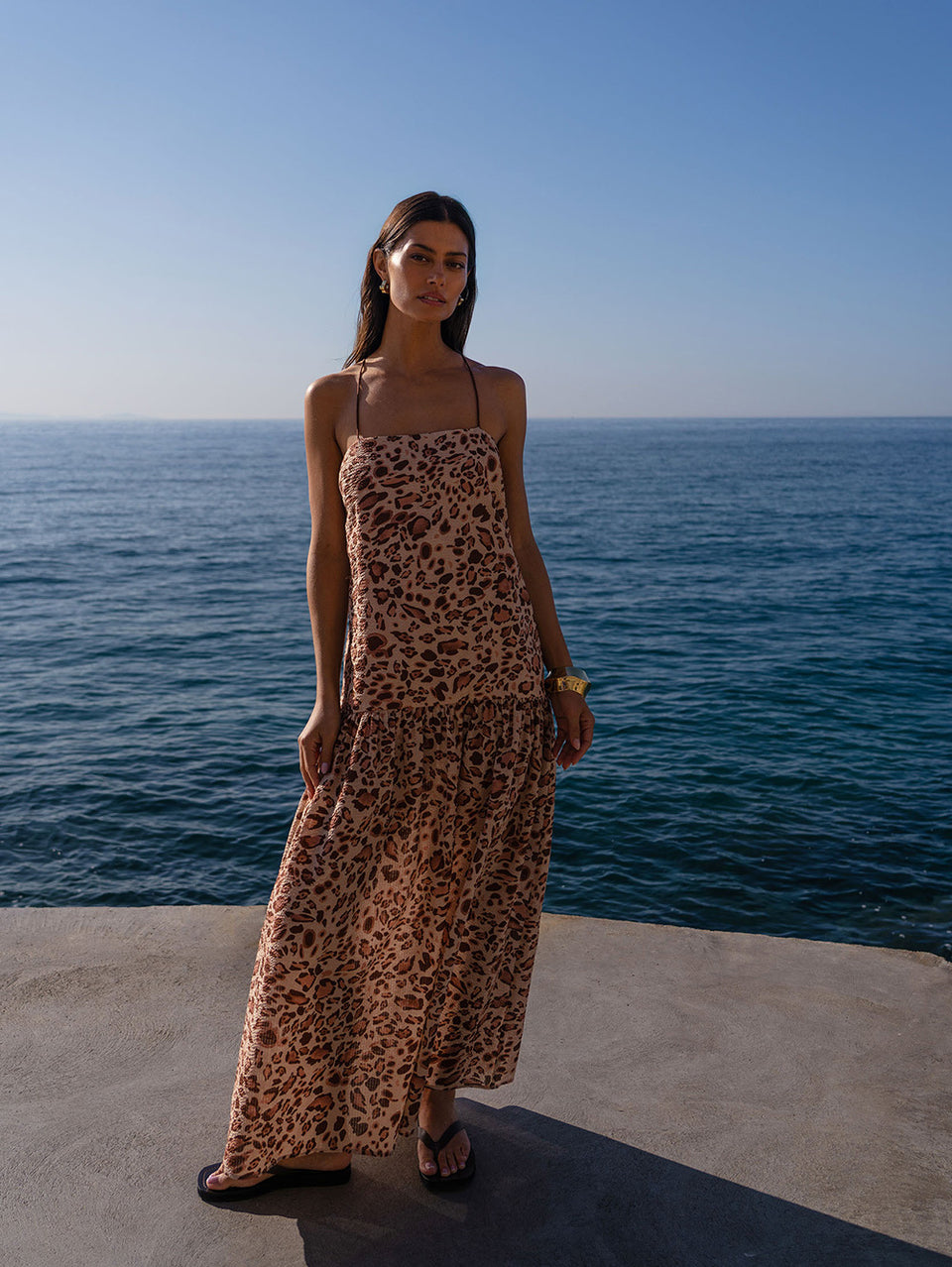 Woman in a leopard print dress standing by the ocean