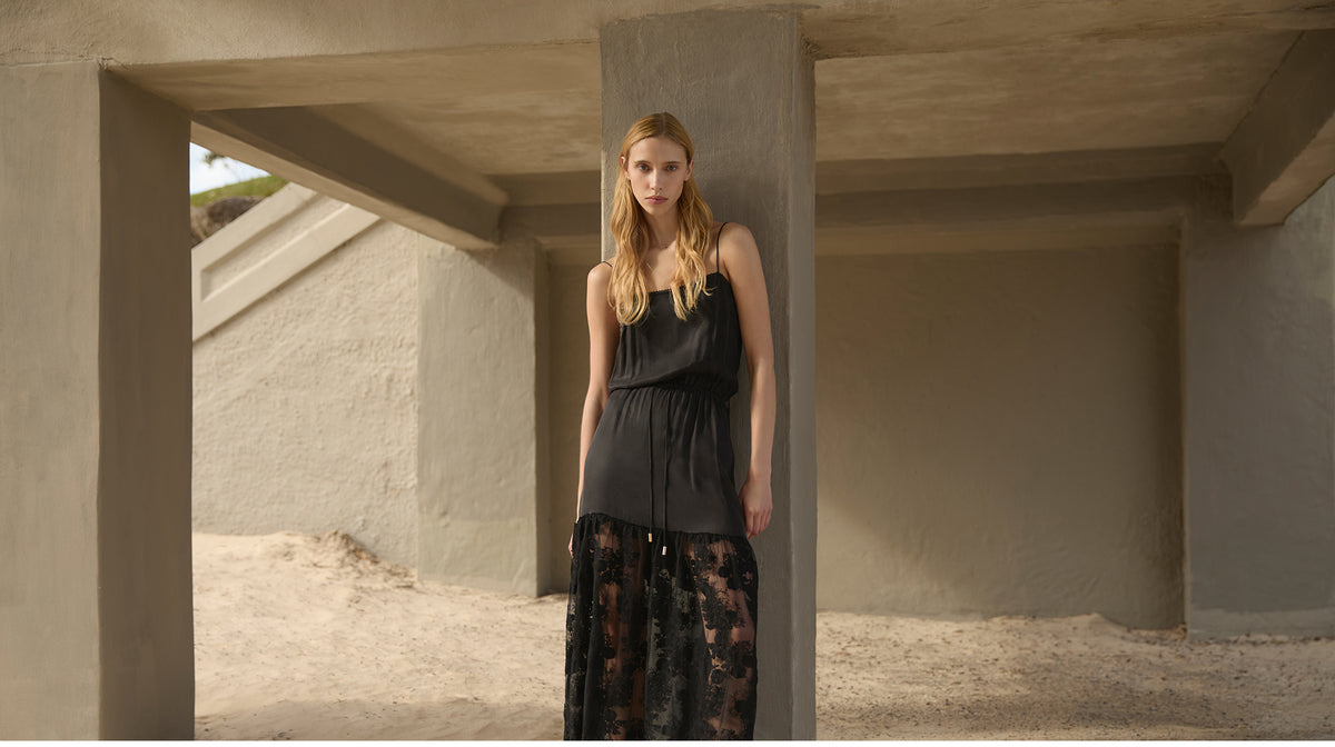 KIVARI black slip dress with sheer floral lace hem – Spring 26 campaign against concrete architecture